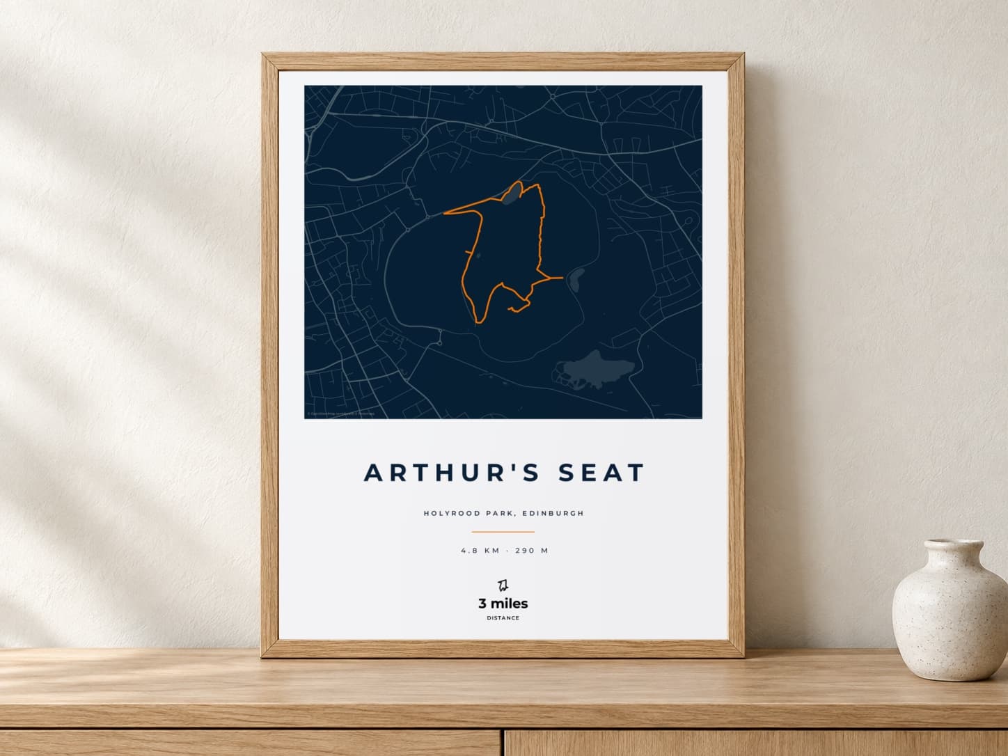 Arthur's Seat Race Blueprint route print in a light oak frame on a console