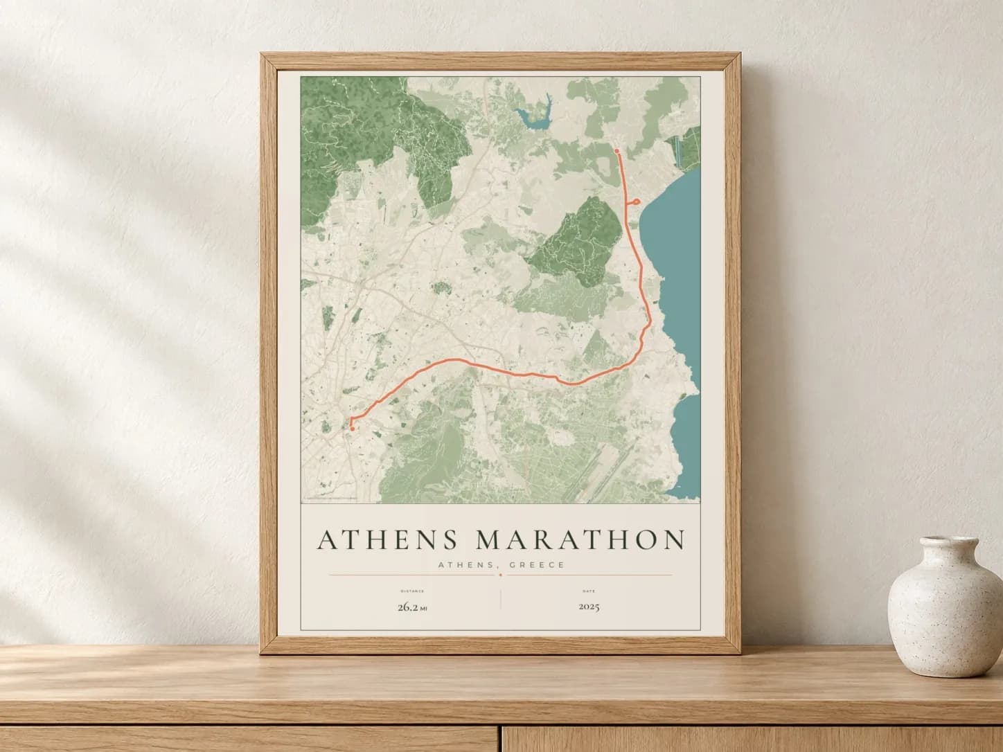 Athens Marathon 2025 Parkland route print in a light oak frame on a console