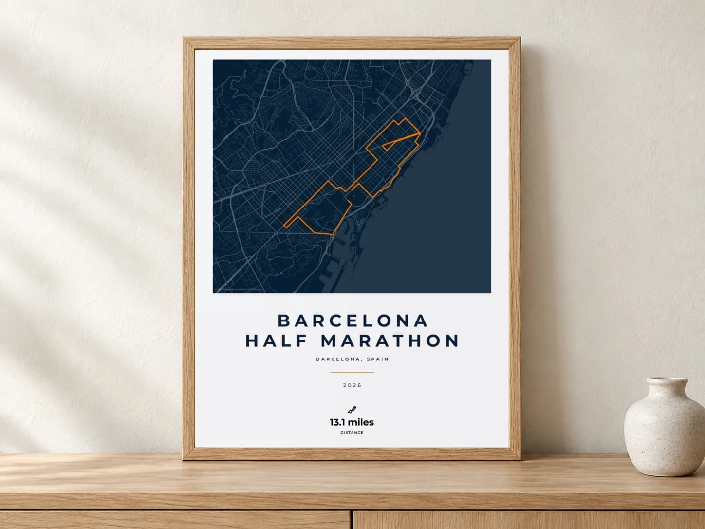 Barcelona Half Marathon 2026 Race Blueprint route print in a light oak frame on a console