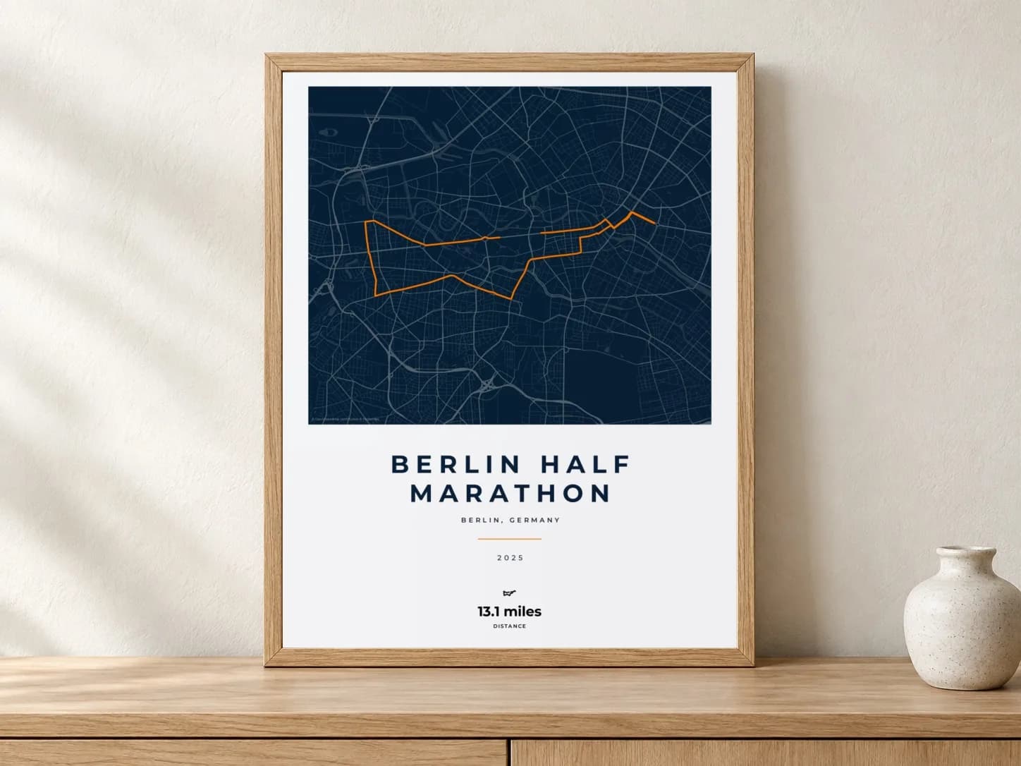 Berlin Half Marathon 2025 Race Blueprint route print in a light oak frame on a console