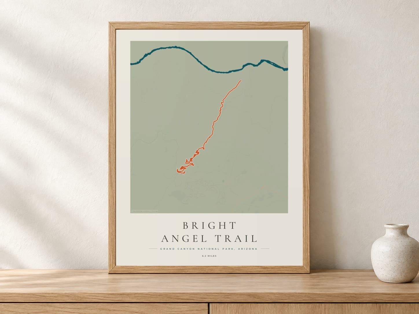 Bright Angel Trail Coastal Atlas route print in a light oak frame on a console