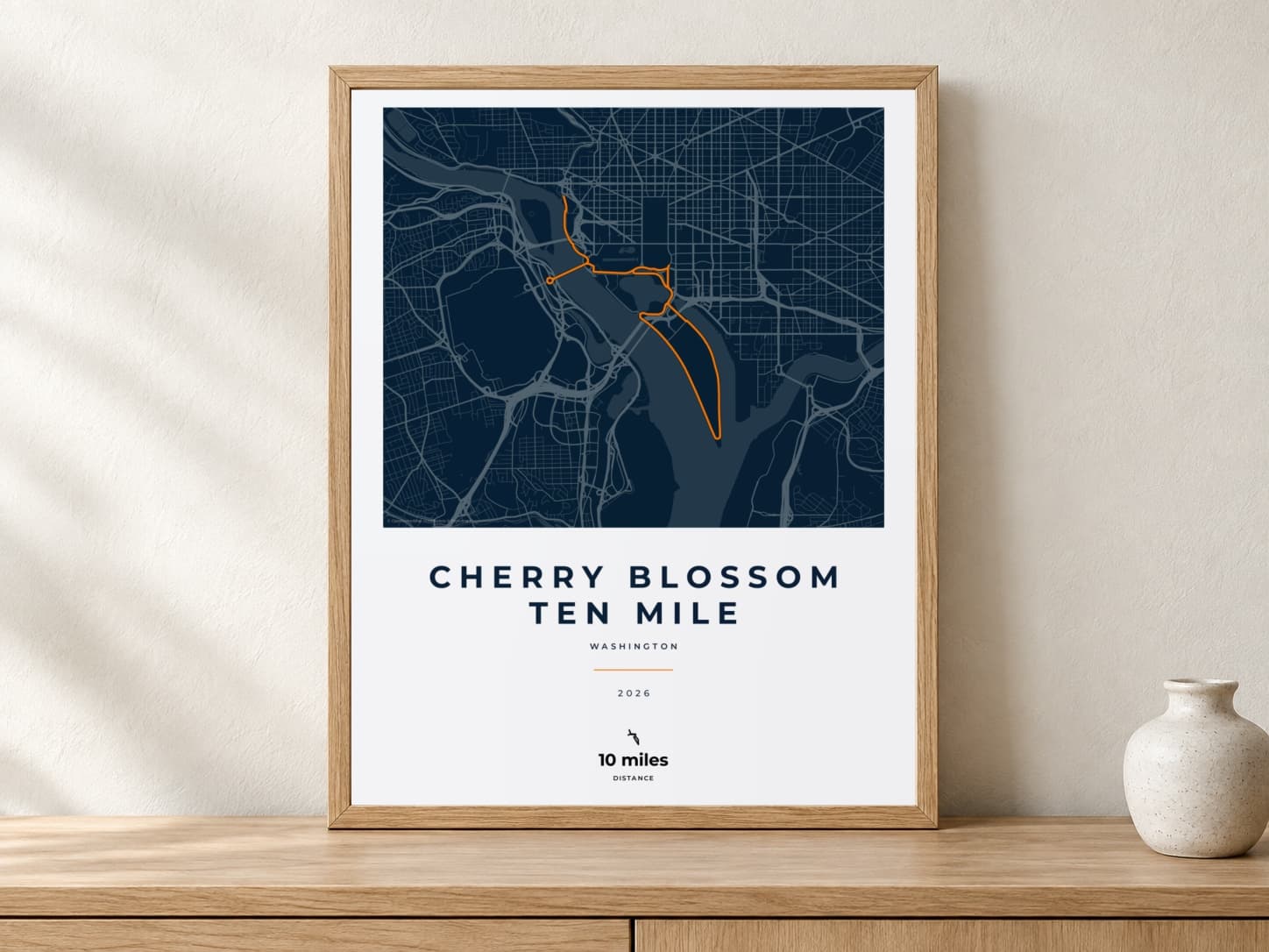 Cherry Blossom Ten Mile 2026 Race Blueprint route print in a light oak frame on a console