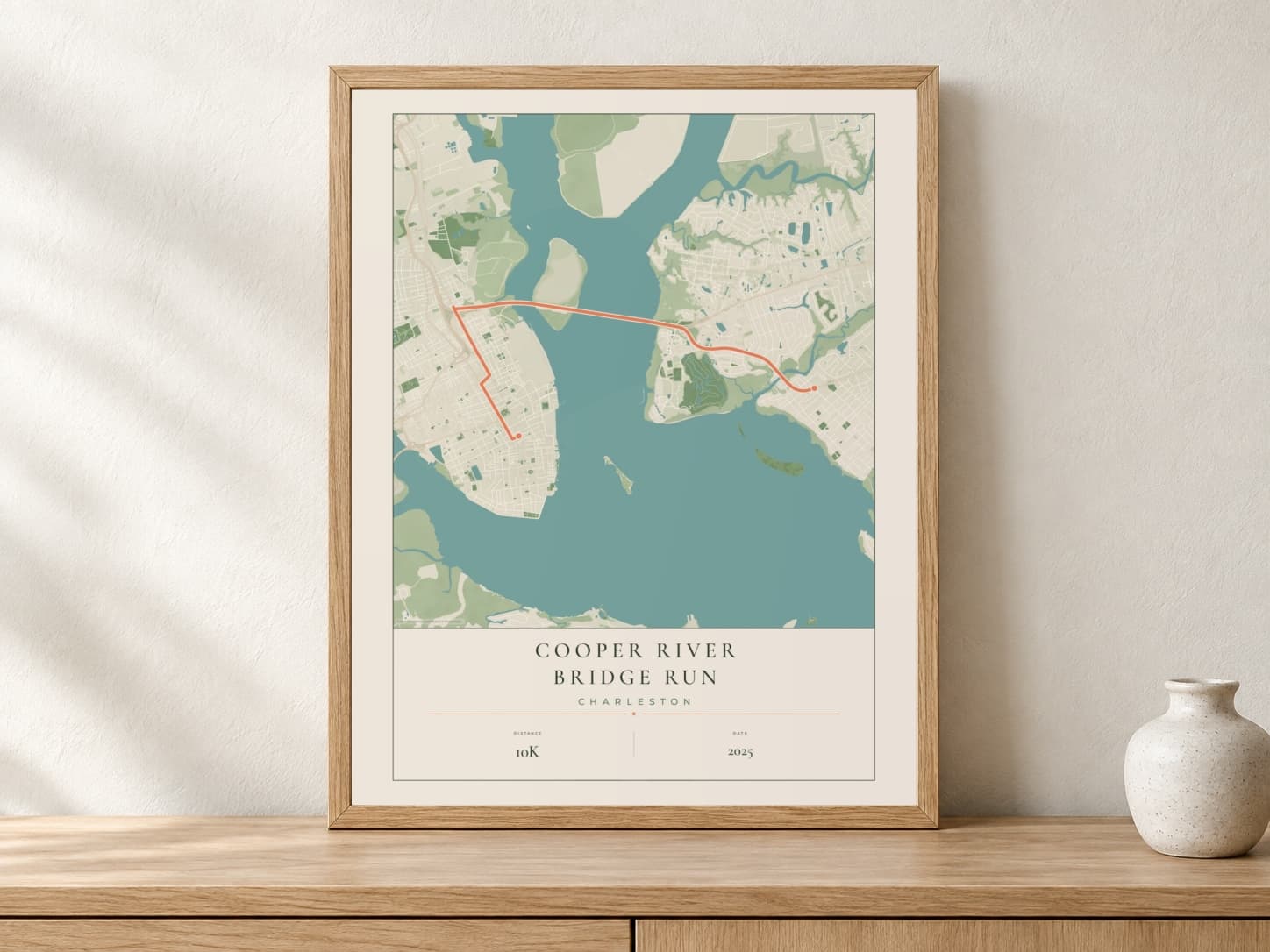 Cooper River Bridge Run 2025 Parkland route print in a light oak frame on a console