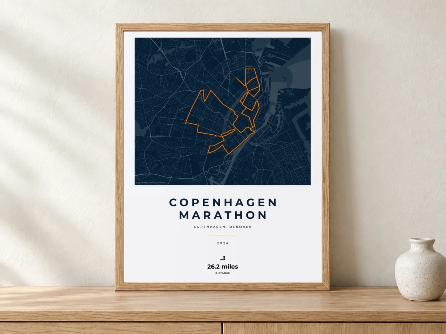 Copenhagen Marathon 2024 Race Blueprint route print in a light oak frame on a console