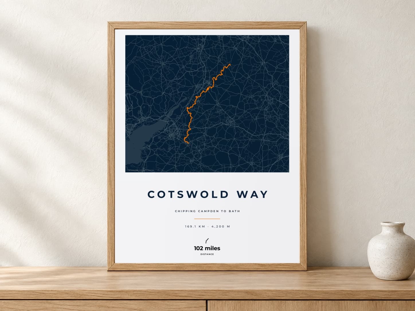 Cotswold Way Race Blueprint route print in a light oak frame on a console