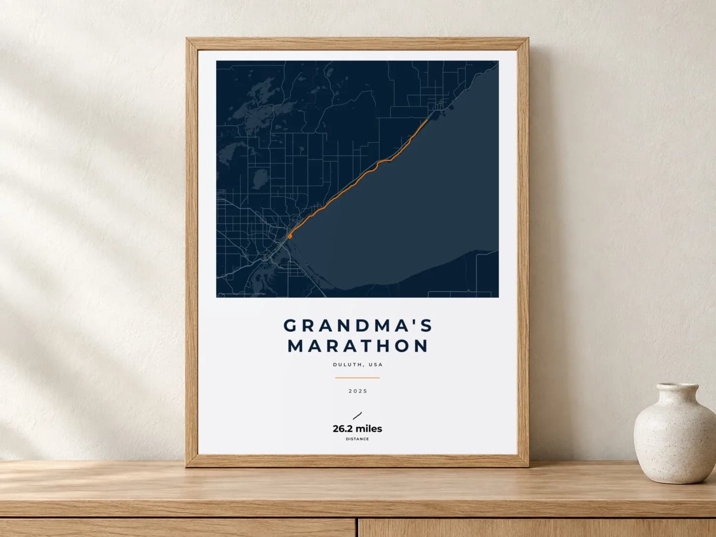 Grandma's Marathon 2025 Race Blueprint route print in a light oak frame on a console