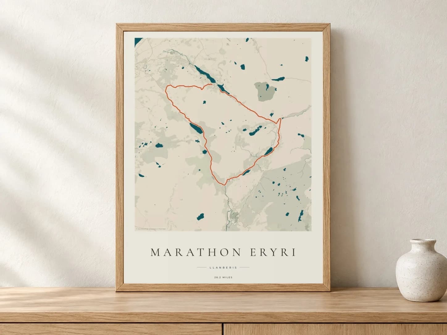 Marathon Eryri 2026 Coastal Atlas route print in a light oak frame on a console