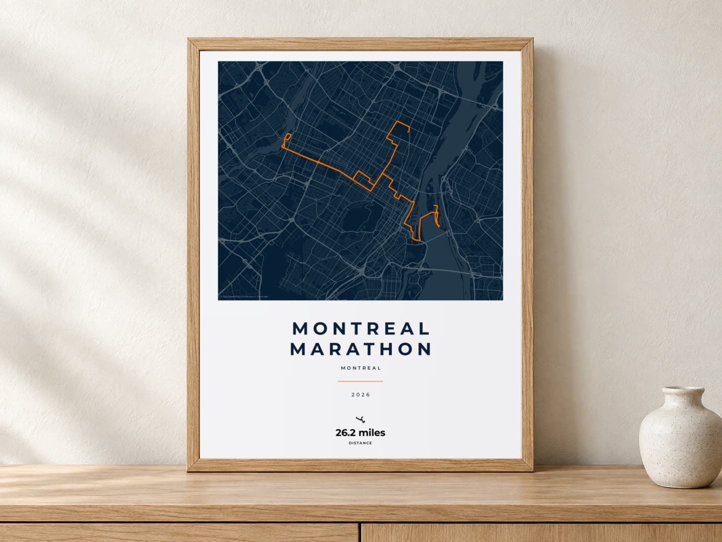 Montreal Marathon 2026 Race Blueprint route print in a light oak frame on a console