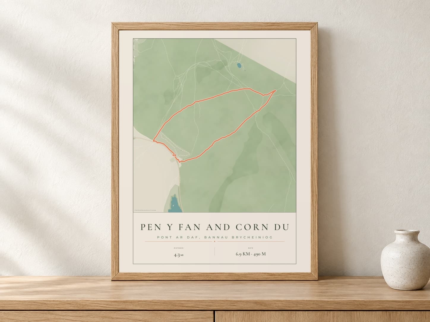 Pen y Fan Parkland route print in a light oak frame on a console