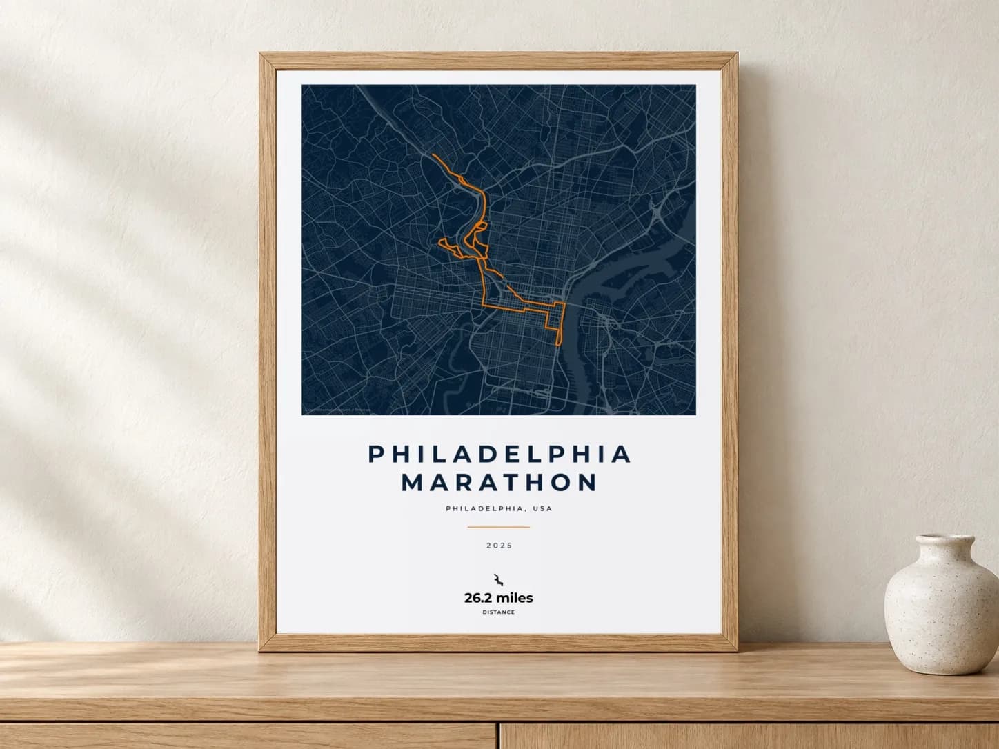 Philadelphia Marathon 2025 Race Blueprint route print in a light oak frame on a console