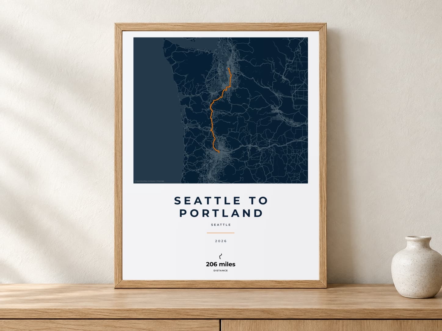 Seattle to Portland 2026 Race Blueprint route print in a light oak frame on a console