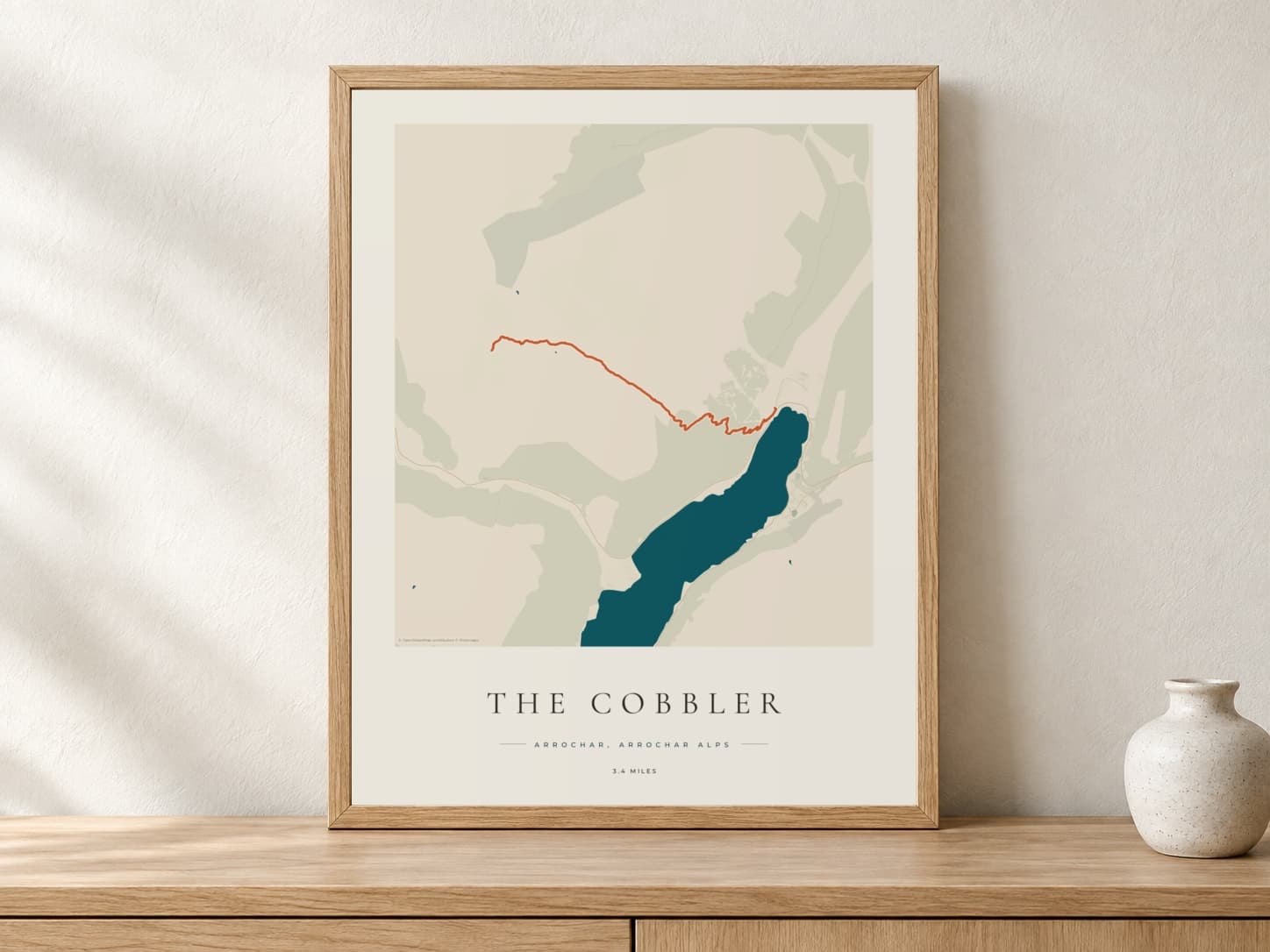 The Cobbler Coastal Atlas route print in a light oak frame on a console