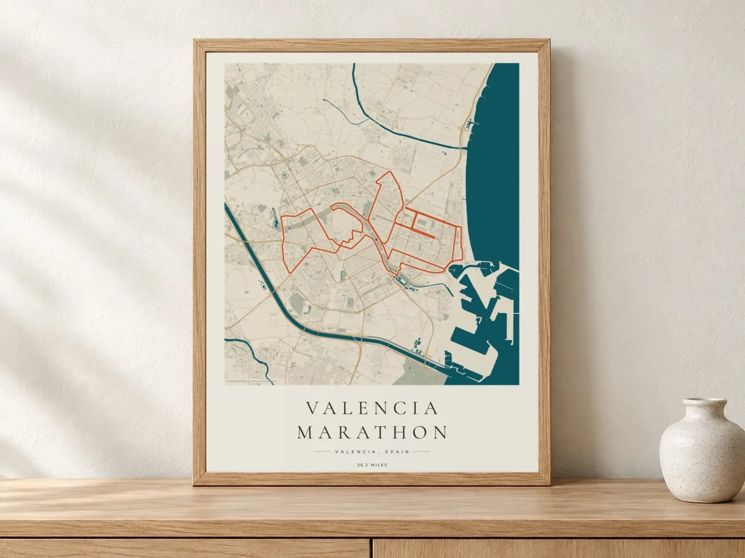 Valencia Marathon 2025 Coastal Atlas route print in a light oak frame on a console