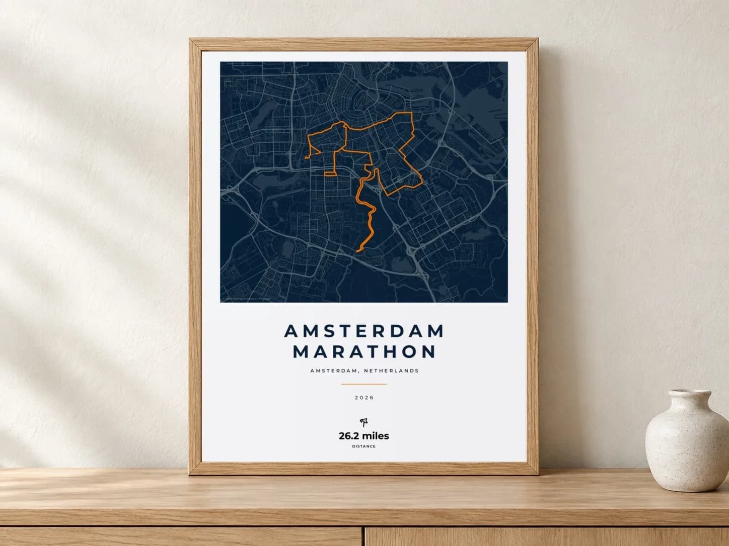 Amsterdam Marathon 2026 Race Blueprint route print in a light oak frame on a console