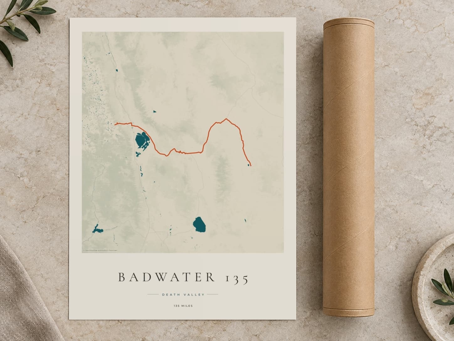 Cardboard postal tube beside a flat Badwater 135 route print