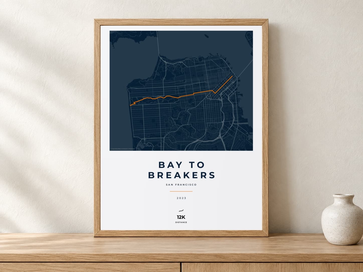 Bay to Breakers 2023 Race Blueprint route print in a light oak frame on a console