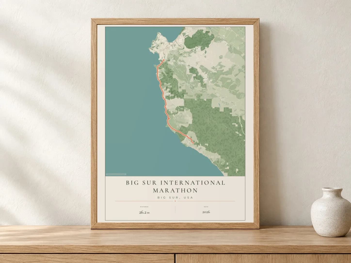 Big Sur International Marathon 2026 Parkland route print in a light oak frame on a console