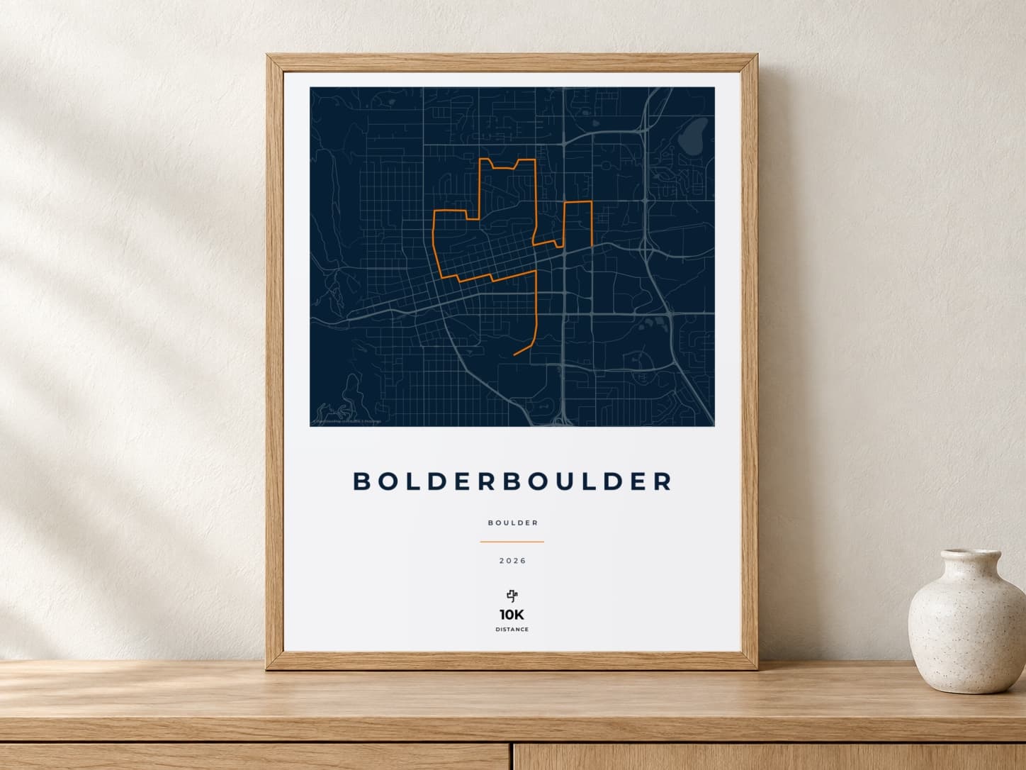 BOLDERBoulder 2026 Race Blueprint route print in a light oak frame on a console