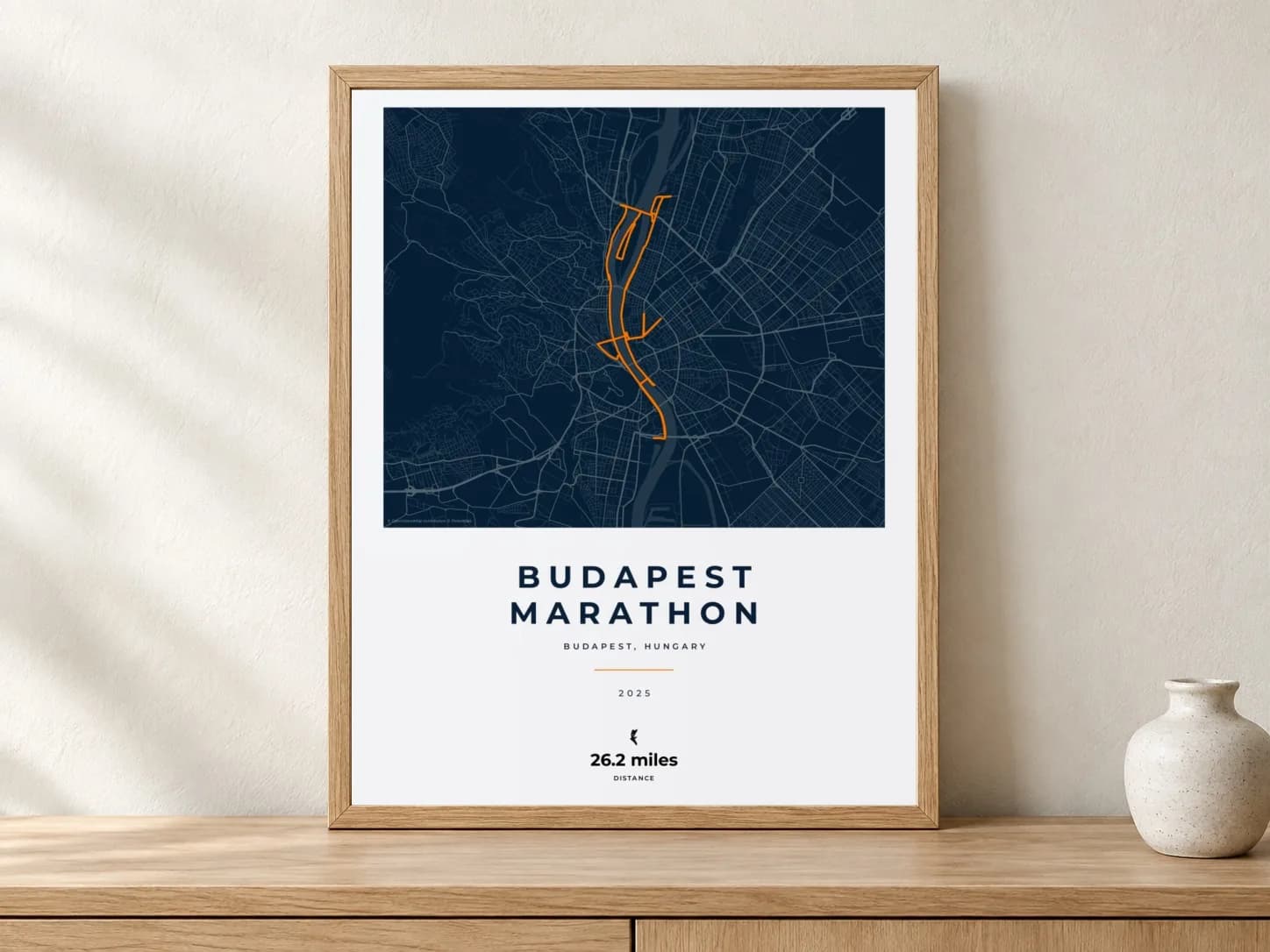 Budapest Marathon 2025 Race Blueprint route print in a light oak frame on a console