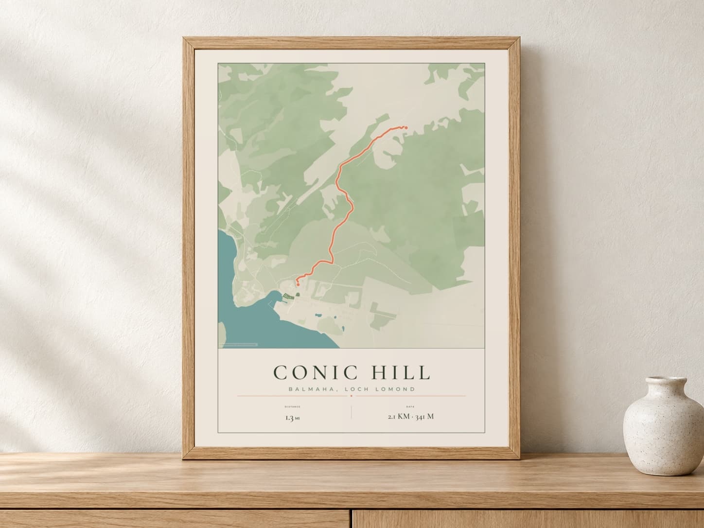 Conic Hill Parkland route print in a light oak frame on a console