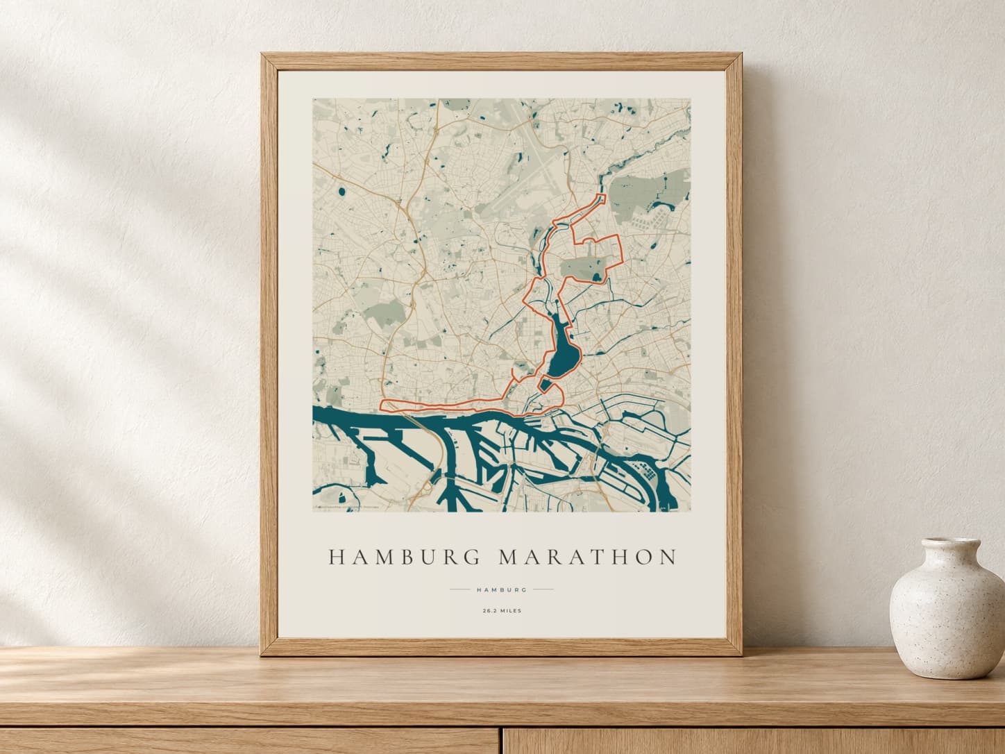 Hamburg Marathon 2026 Coastal Atlas route print in a light oak frame on a console