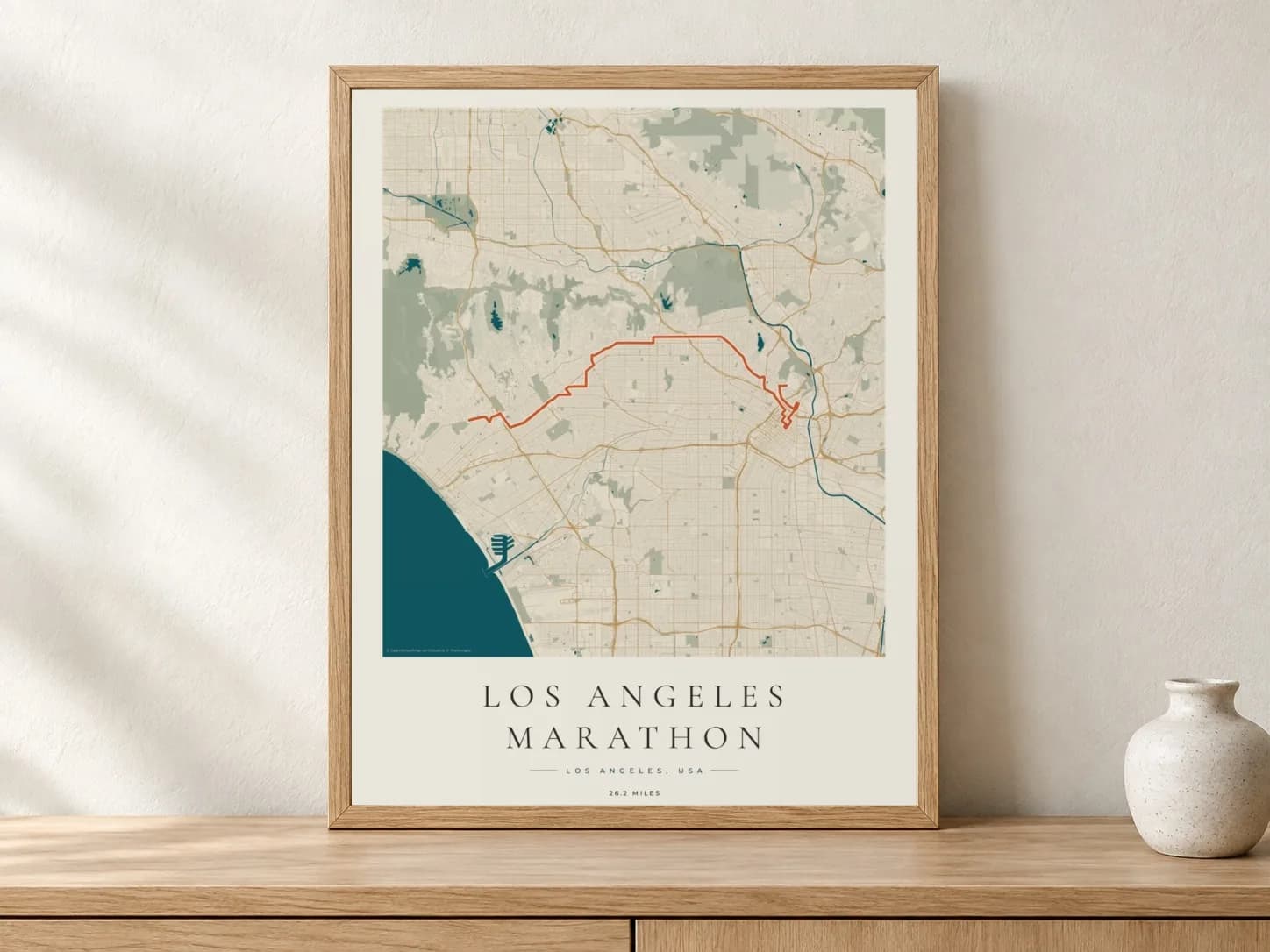 Los Angeles Marathon 2026 Coastal Atlas route print in a light oak frame on a console