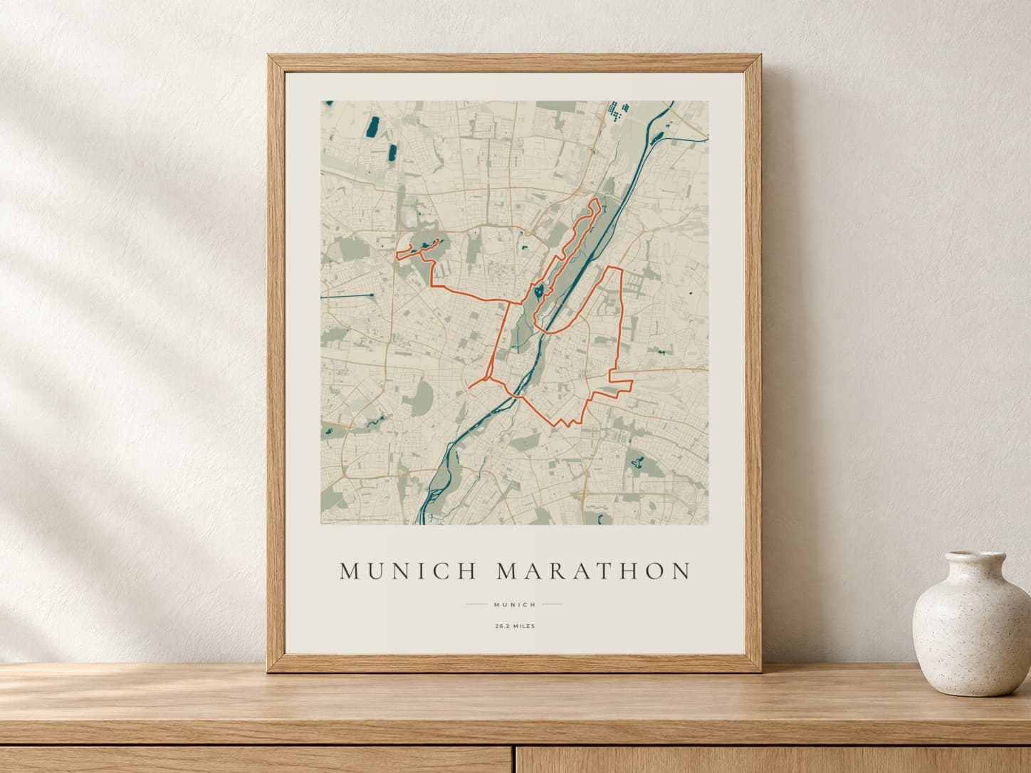 Munich Marathon 2025 Coastal Atlas route print in a light oak frame on a console