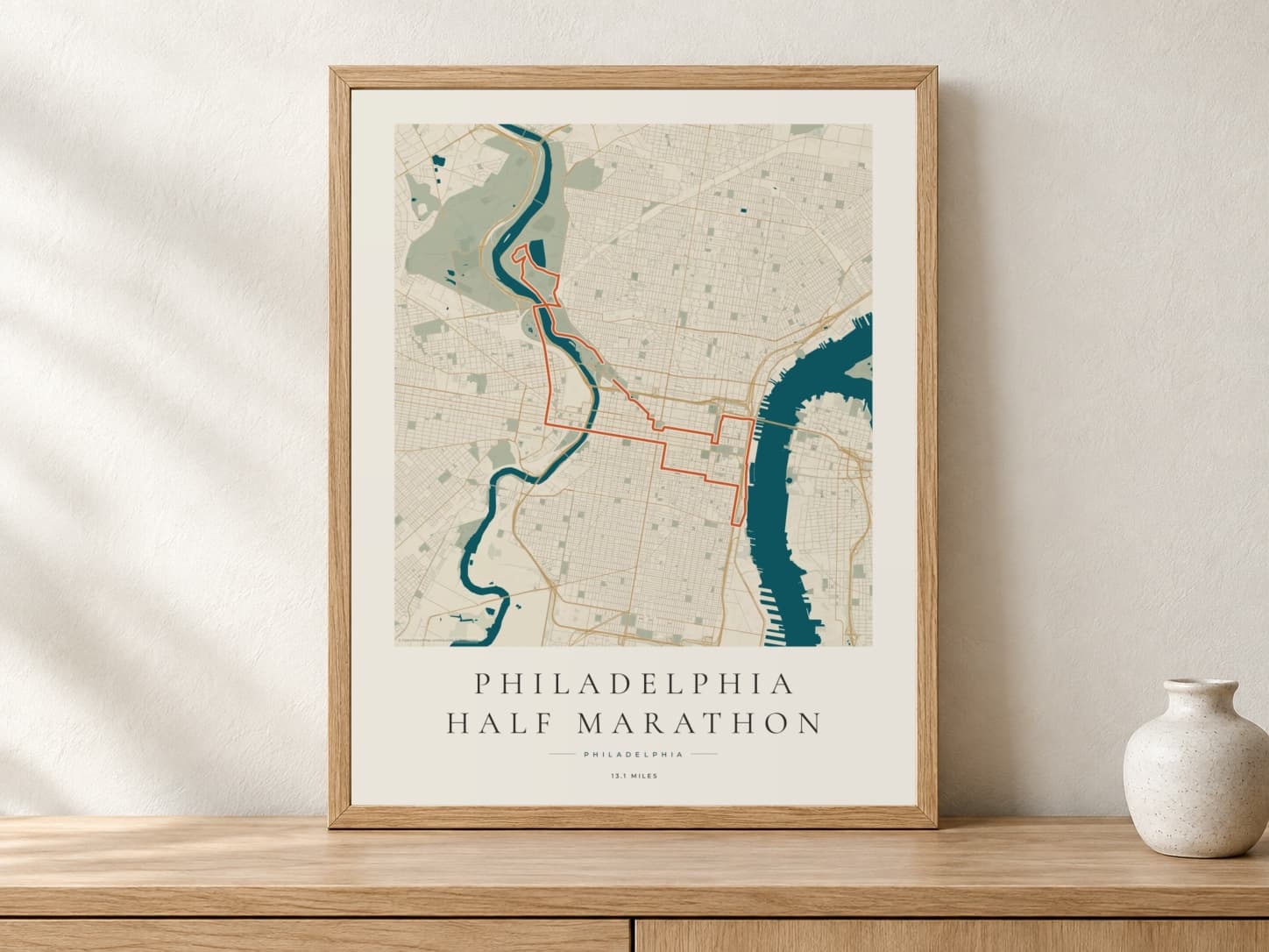 Philadelphia Half Marathon 2026 Coastal Atlas route print in a light oak frame on a console