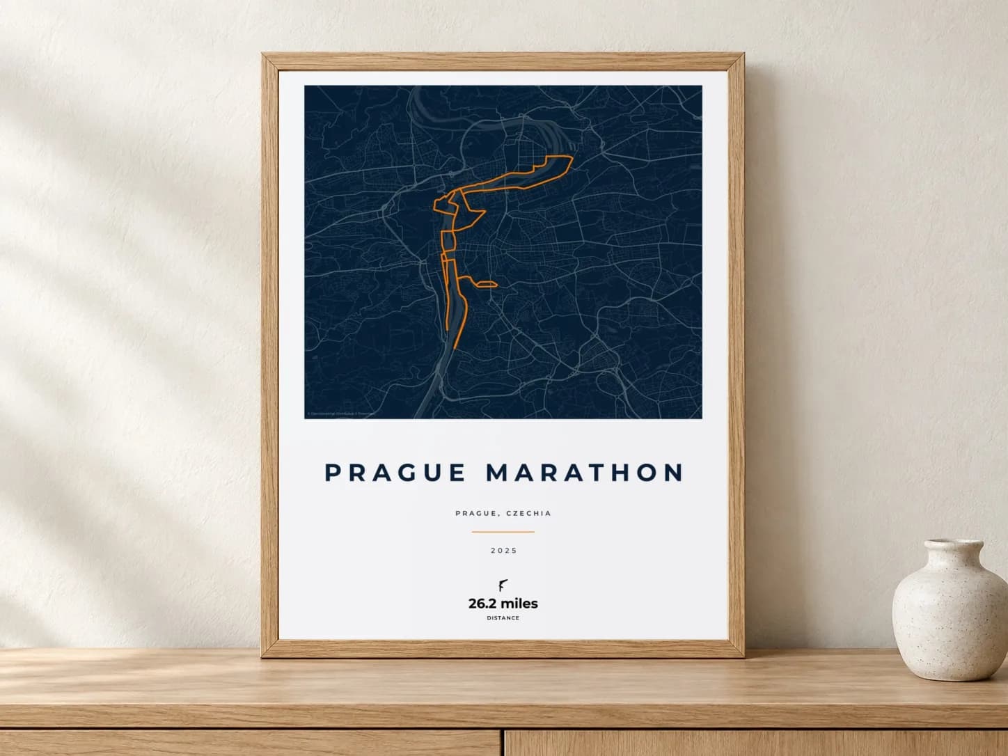 Prague Marathon 2025 Race Blueprint route print in a light oak frame on a console