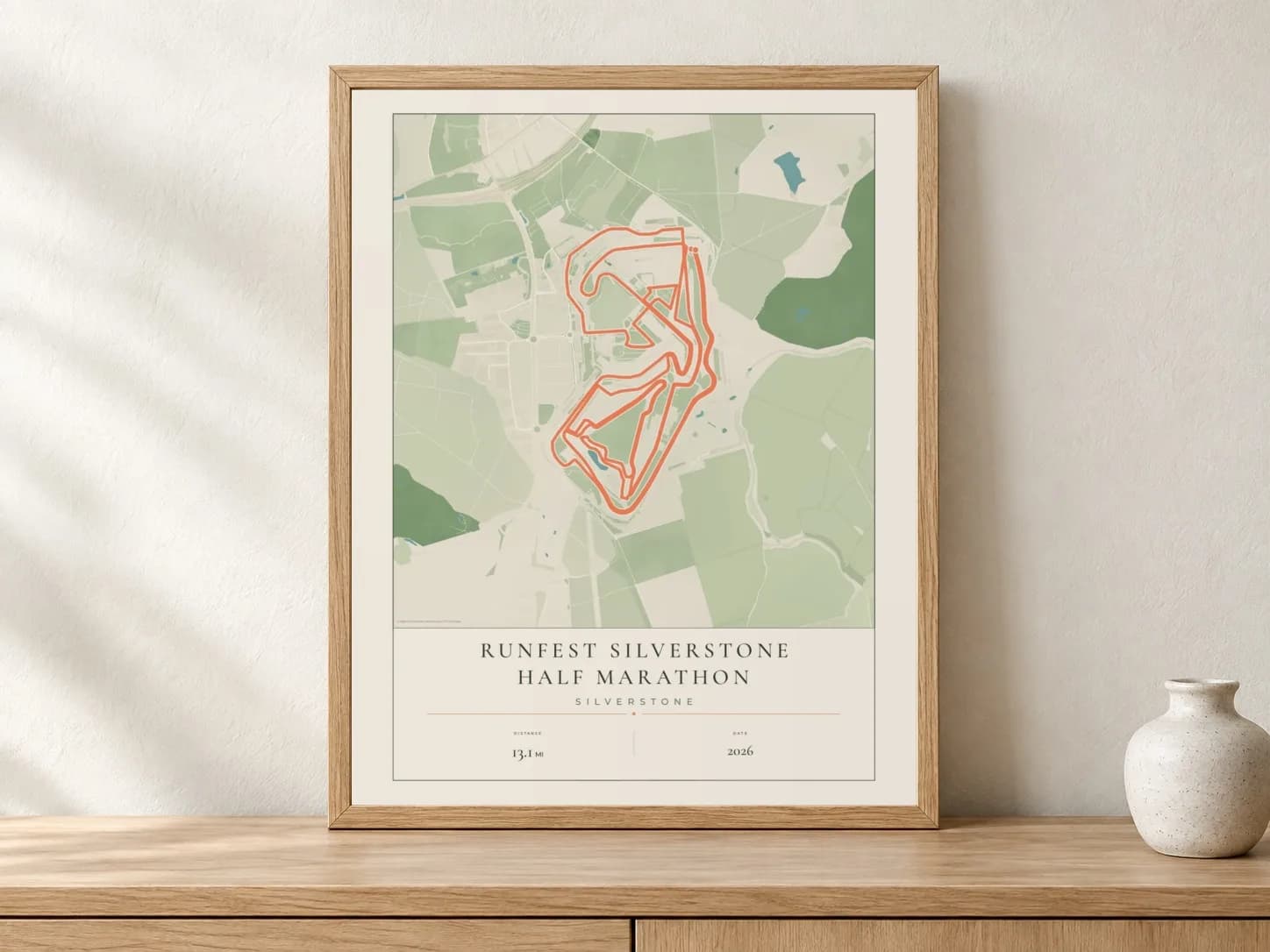 RunFest Silverstone Half Marathon Parkland route print in a light oak frame on a console