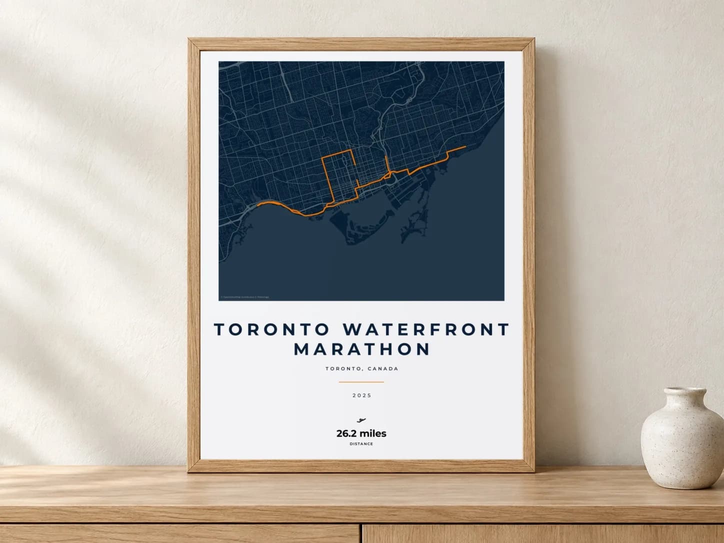 Toronto Waterfront Marathon 2025 Race Blueprint route print in a light oak frame on a console