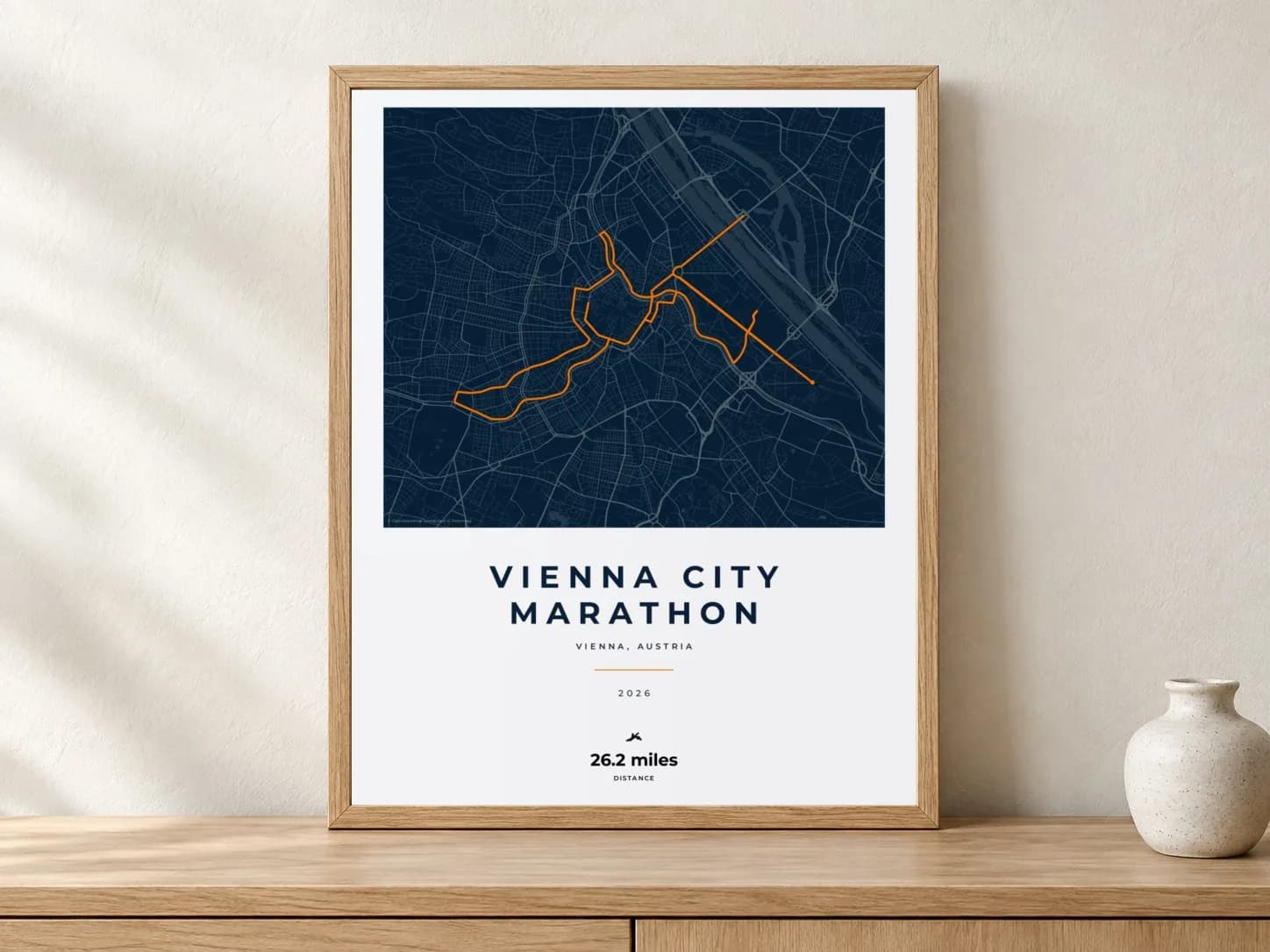Vienna City Marathon 2026 Race Blueprint route print in a light oak frame on a console