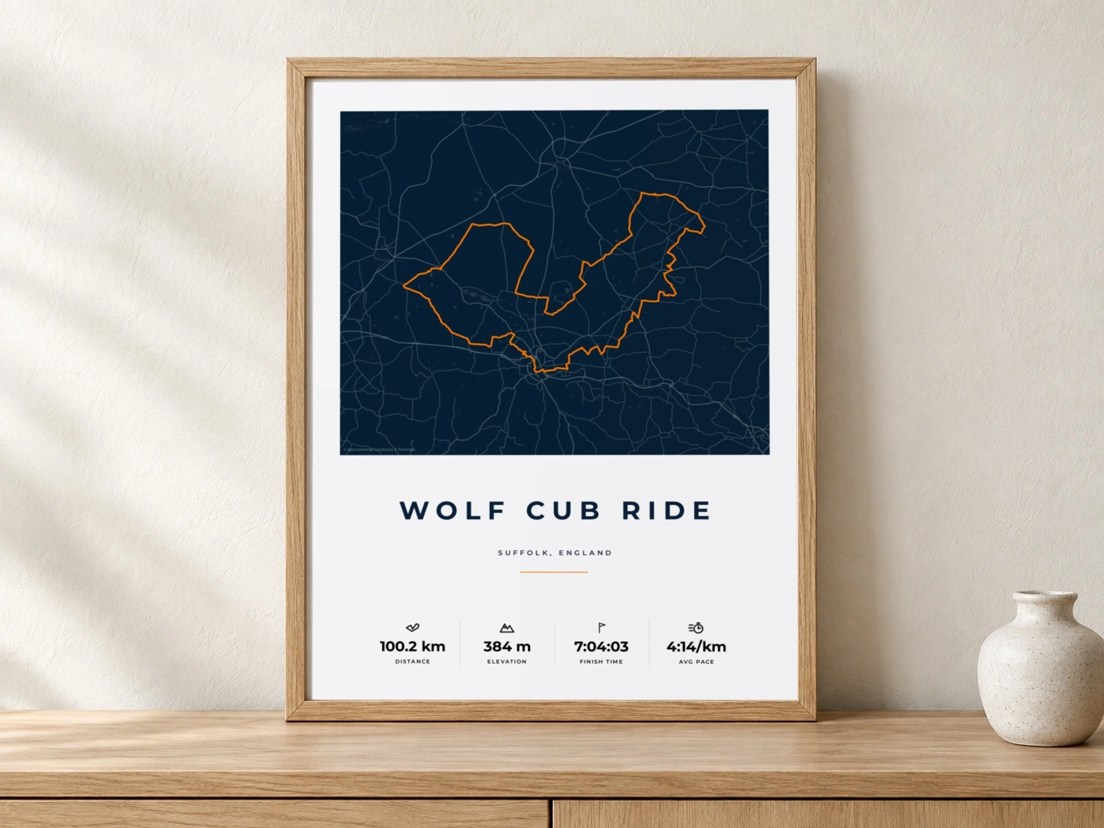 Wolf Cub cycling print in an oak frame against a quiet plaster wall