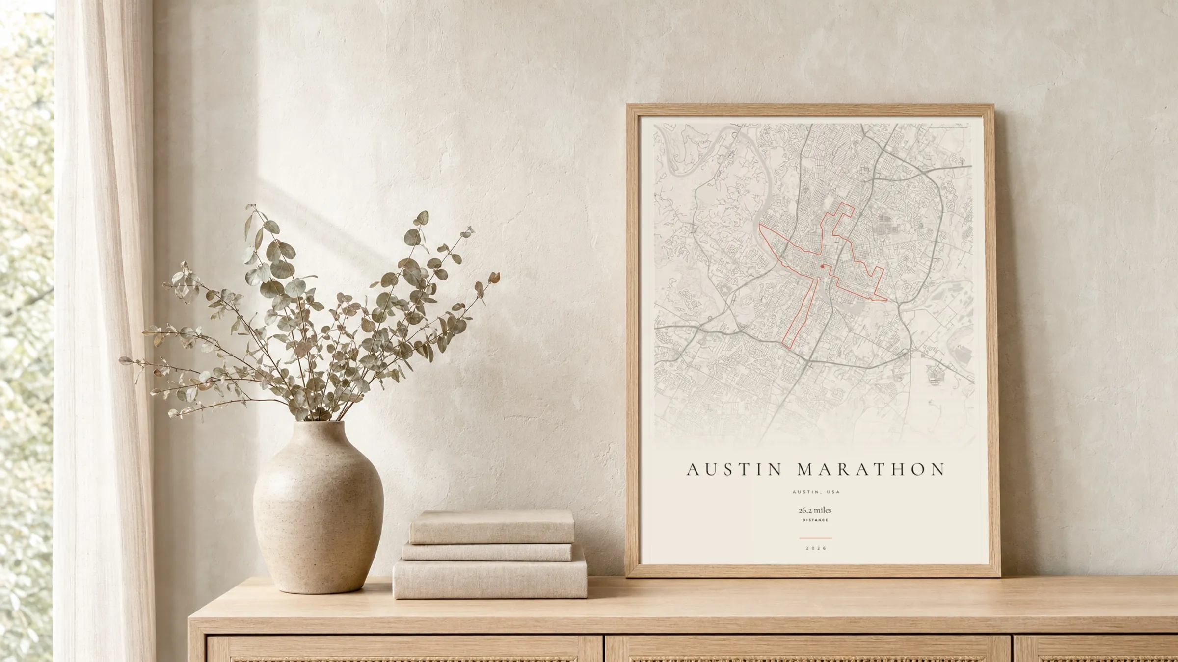 Austin Marathon 2026 Gallery Mono route print in a light oak frame on a rattan console