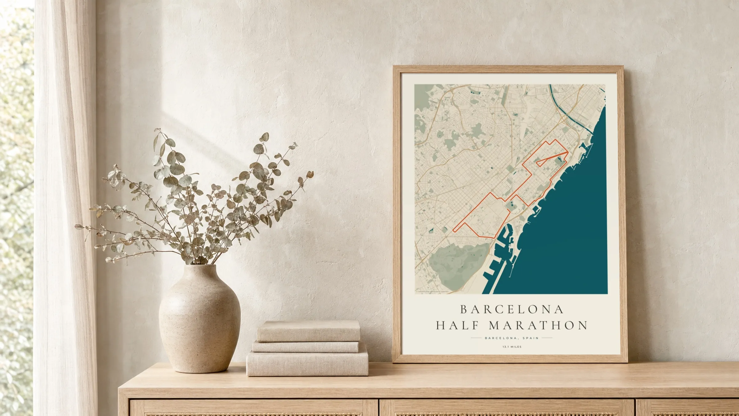 Barcelona Half Marathon 2026 Coastal Atlas route print in a light oak frame on a rattan console