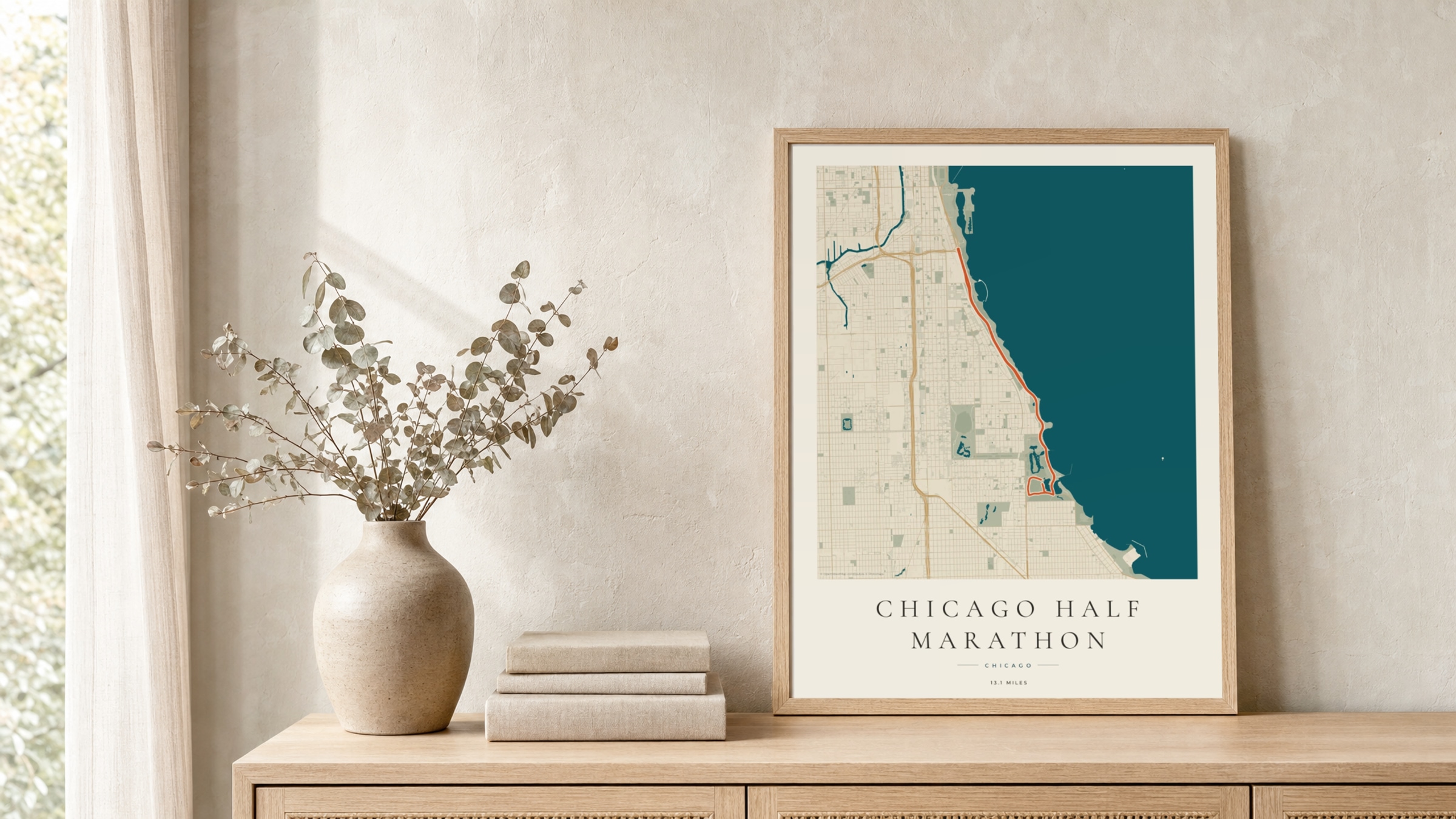 Chicago Half Marathon 2025 Coastal Atlas route print in a light oak frame on a rattan console