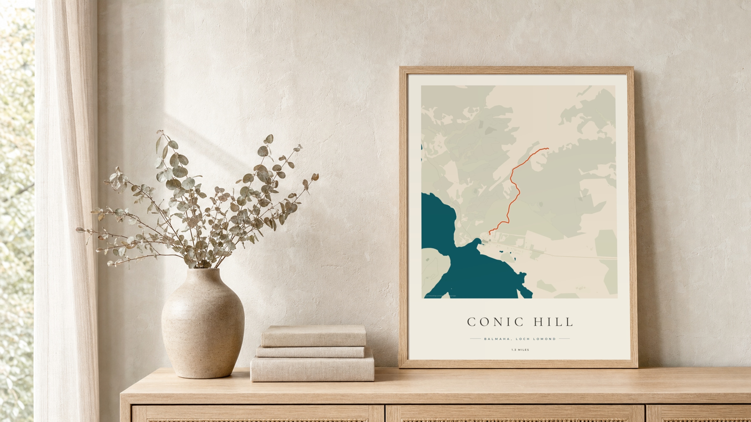 Conic Hill Coastal Atlas route print in a light oak frame on a rattan console