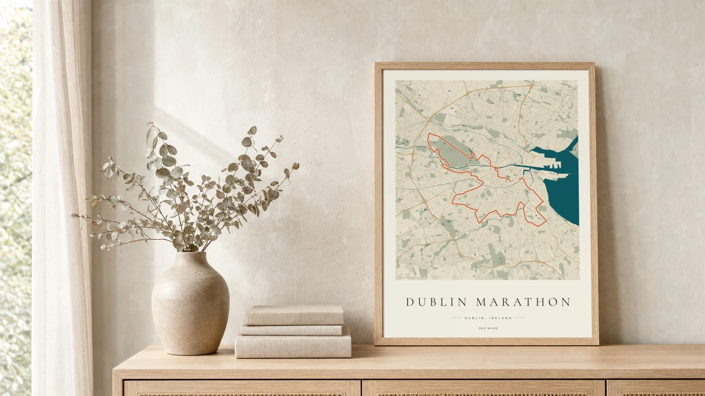 Dublin Marathon 2025 Coastal Atlas route print in a light oak frame on a rattan console