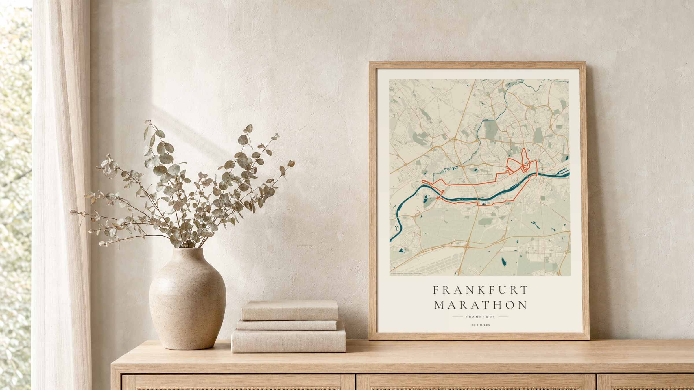 Frankfurt Marathon 2024 Coastal Atlas route print in a light oak frame on a rattan console