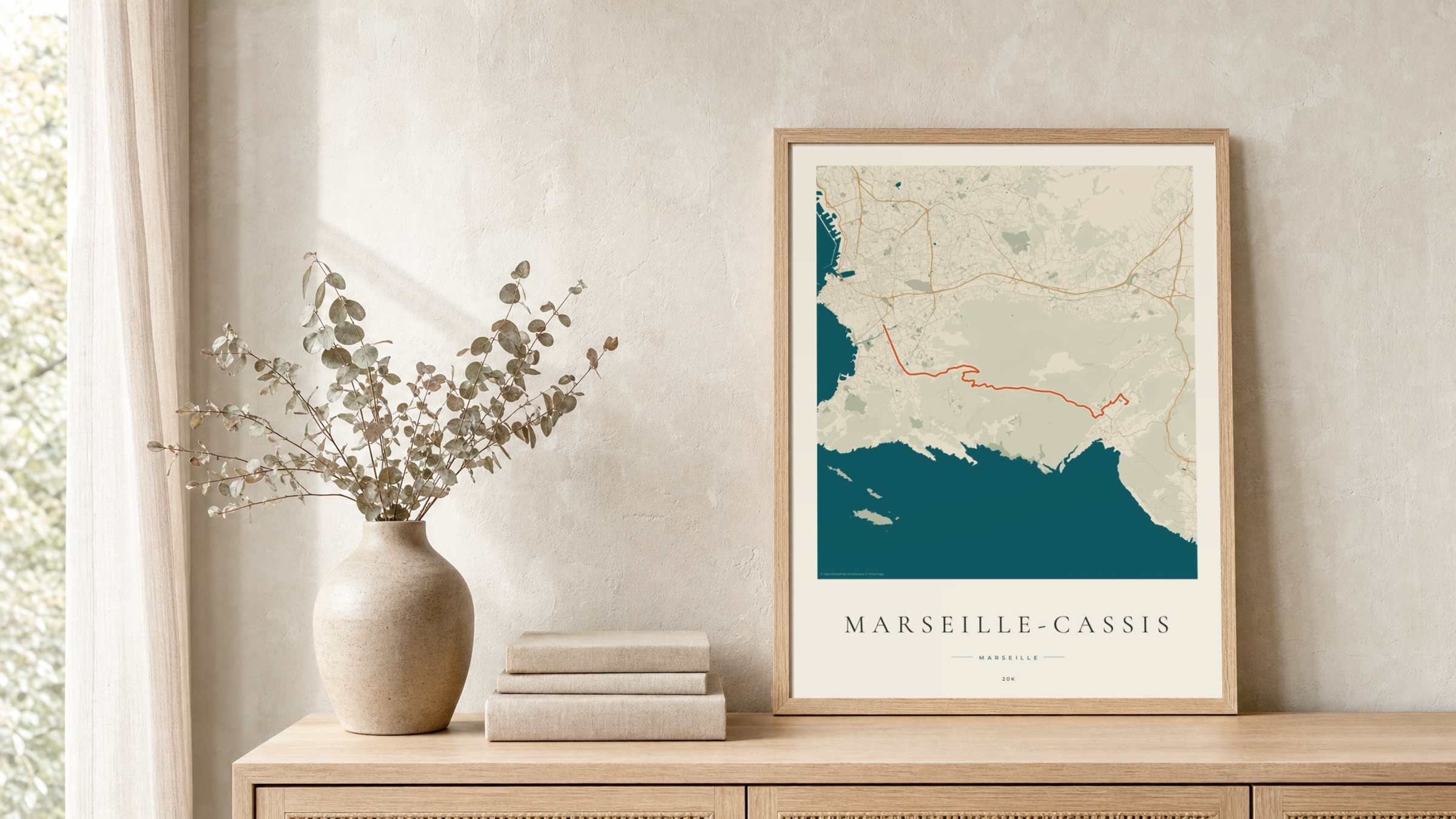 Marseille-Cassis 2026 Coastal Atlas route print in a light oak frame on a rattan console