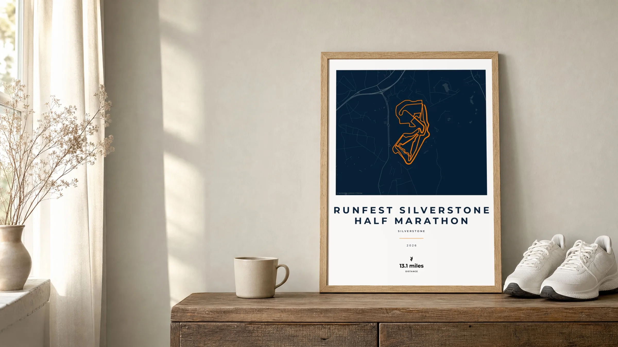 RunFest Silverstone Half Marathon Race Blueprint route print in an oak frame on a sideboard beside running shoes